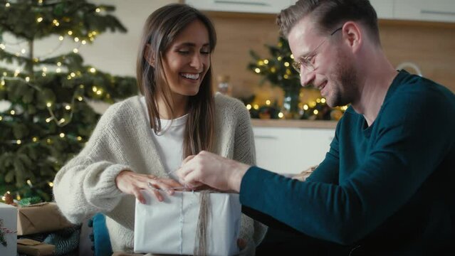 Caucasian couple packing Christmas presents together at home. Shot with RED helium camera in 8K. 