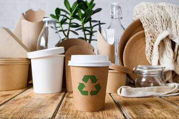 The concept of zero waste and no plastic. Close-up of a disposable paper cup with a recycling sign on the background of eco-friendly items.