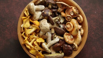 Various kinds of assorted raw mushrooms placed in wooden bowl