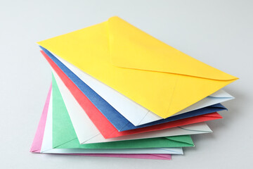 Stack of colorful paper envelopes on light background