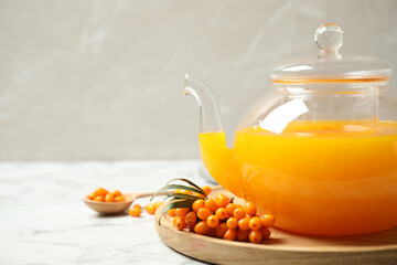 Delicious sea buckthorn tea on white marble table, closeup. Space for text