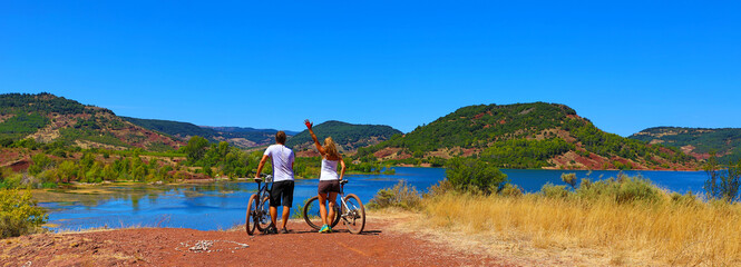 Sporty couple with bike, lake and mountain ( Salagou lake,  France)