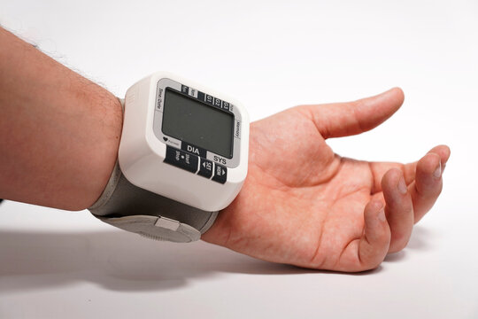 Man's Hand With Wrist Blood Pressure Monitor On White Background