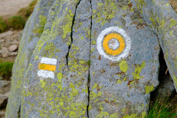 Yellow difficulty tourist hike sign on the top of the mountain on a stone in the Tatras.