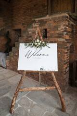 Welcome sign to wedding, wooden frame natural wood with flowers bouquet floral display.  Standing...