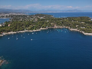 Naklejka na ściany i meble Aerial view of Cap d'Antibes and Billionaire's Bay. Beautiful rocky beach near coastal path on the Cap d'Antibes, Antibes, France. Drone view from above of Côte d’Azur near Juan-les-Pins and Cannes.
