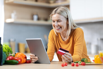 Happy blonde woman buying food online, using digital pad