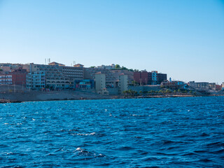 Panorama of sea waves against the backdrop of the coast and blue sky.