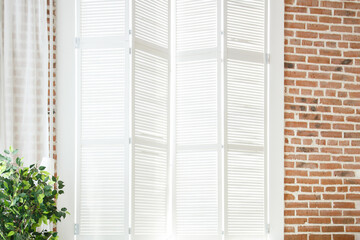 white window frame with wooden shutters in red brick wall