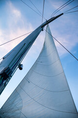 Bottom view mast boat against sky with cumulus clouds in sea. Mast of sailing yacht with ropes with...