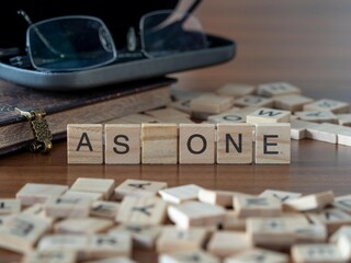 as one word or concept represented by wooden letter tiles on a wooden table with glasses and a book