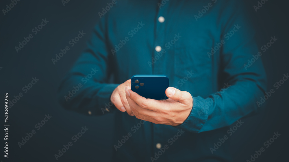 Poster Closeup image of a man holding and using mobile phone or smartphone in room.