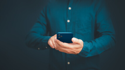 Closeup image of a man holding and using mobile phone or smartphone in room.