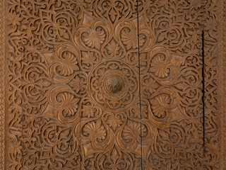 Closeup view of intricate traditional islamic wood carving of beautiful floral and geometric design on ancient door, Istaravshan, Sughd region, Tajikistan