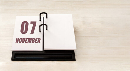 november 7. 7th day of month, calendar date. Stand for desktop calendar on beige wooden background. Concept of day of year, time planner, autumn month