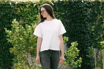 Woman wearing white t-shirt with space for logo or design in the park in summer