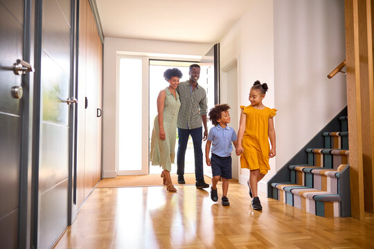 Family Coming Home After Day Out Opening Front Door And Walking Into Hallway
