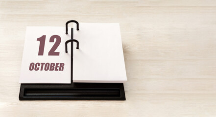 october 12. 12th day of month, calendar date. Stand for desktop calendar on beige wooden background. Concept of day of year, time planner, autumn month