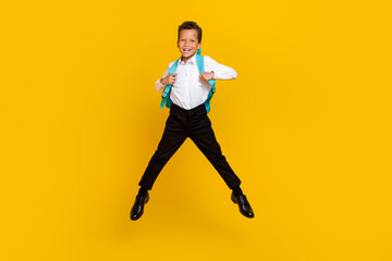 Fototapeta na wymiar Full length portrait of active energetic boy jumping carry backpack isolated on yellow color background