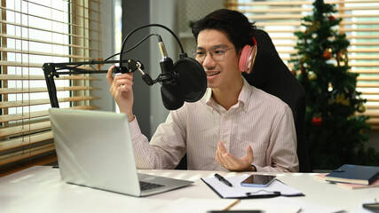 Handsome man wearing headphone recording podcast from home studio. Radio, podcasts, blogging and technology concept