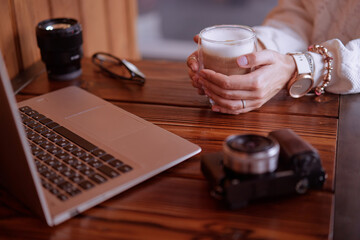 Working place of internet blogger with a woman typing on a laptop or drinking cappuccino coffee.