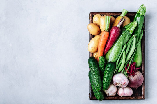 Fresh organic vegetables box with potatoes, zucchini, green beans, carrots, garlic, cucumbers and beets.