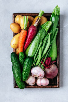 Fresh organic vegetables box with potatoes, zucchini, green beans, carrots, garlic, cucumbers and beets.