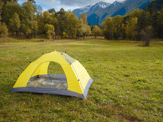 trip to Caucasus mountains, Arkhyz, Teberdinsky reserve. concept of discovery and exploration of wild places in early autumn. yellow tent in autumn valley