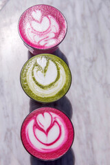 Colorful Beetroot, matcha lattes are on the marble table.