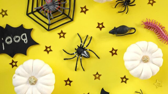 Halloween background with black bats, spiders, pumpkin and stars. Modern Holiday design. Halloween party border spinning on yellow. Flat lay, top view, copy space. Thanksgiving fall trendy decoration.