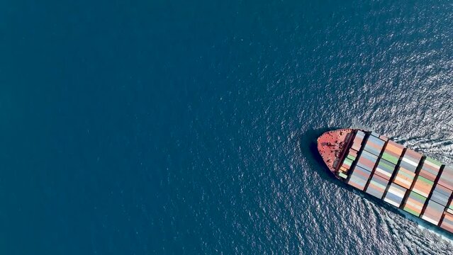 High aerial top view of a large, heavy loaded container cargo vessel crossing the ocean