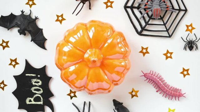 Halloween background with black bats, spiders, pumpkin and stars. Modern Holiday design. Halloween party border spinning on white. Flat lay, top view, copy space. Thanksgiving fall trendy decoration.