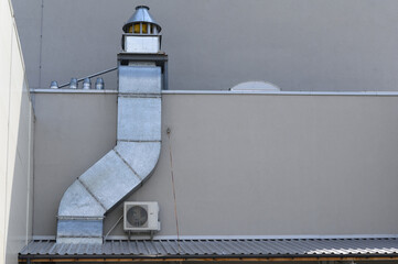 Hood with a pipe behind a restaurant in a shopping center.