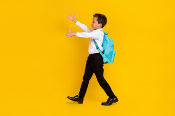 Full length profile portrait of cheerful person walk look raise hands empty space isolated on yellow color background