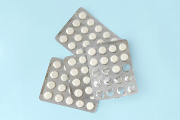 Blisters with white pills close-up on a blue background. View from above. Pharmacies, medicine and health