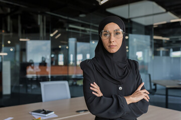 Portrait of female boss in hijab, successful businesswoman serious and focused working inside...
