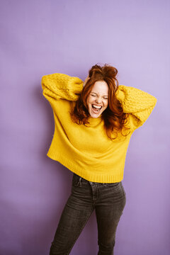 laughing redhead woman tearing her hair, copyspace with purple background