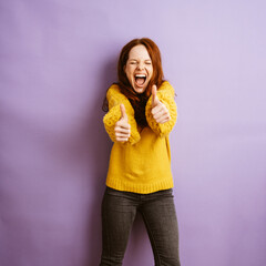 enthusiastic redhead woman shows two thumbs up, copyspace with purple background