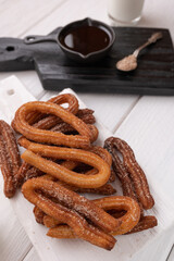 Homemade churros on a white wooden background.