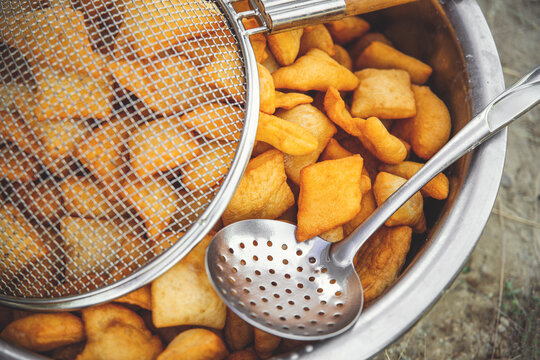 Traditional Kazakh and central asian fresh baursaks in a large dish with a colander and slotted spoon.