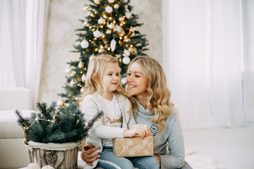 Happy family: mother and daughter. Family in a bright New Year's interior with a Christmas tree