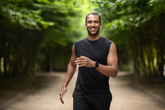 Positive african american guy listening to music while jogging