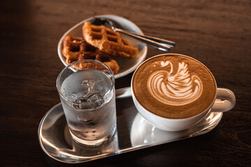 Hot coffee latte with latte art milk foam in a swan shape in cup mug and Homemade Belgian Waffles...