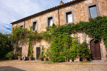 Fototapeta na wymiar Ivy covered building in medieval town in Tuscany, Italy. Brick walls and plants