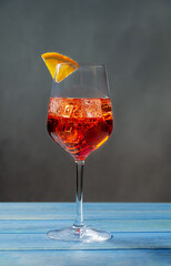 Classic cocktail Americano with campari, soda and Sweet Vermouth with ice and a slice of orange on a blue background.Traditional recipe.