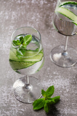 Classic Gin and tonic with cucumber or Tom Collins or Gin Fizz alcoholic cocktail with Gin, tonic, ice, cucumber and mint or mocktail on a grey background