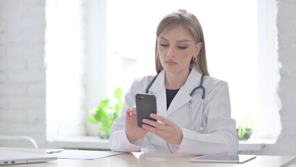 Lady Doctor using Smartphone While sitting in Clinic