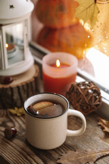 Mug of hot tea with apple and cinnamon on the autumn window. Autumn and fall cozy vertical postcard 