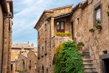 Fototapeta na wymiar Picturesque building in medieval town in Tuscany, Italy. Old stone walls and plants