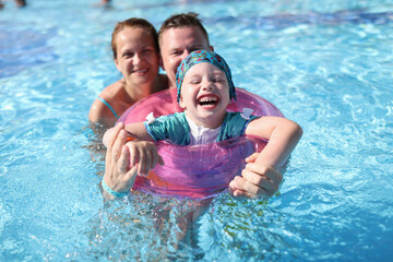 Happy laughing joyful family couple and baby in pool